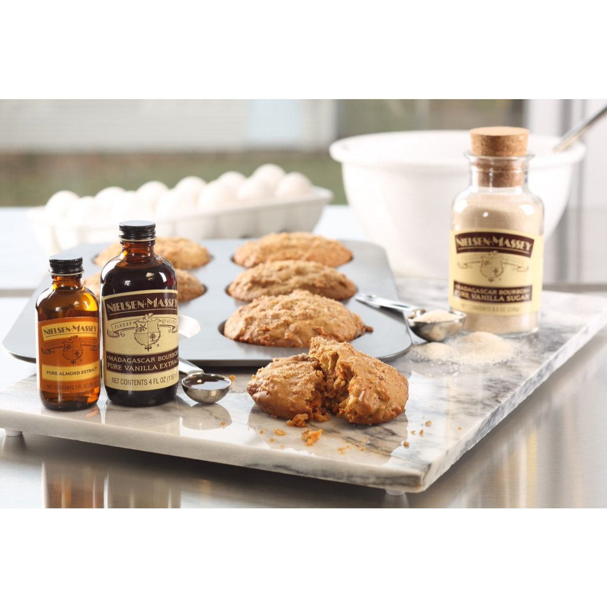 Nielsen-Massey Pure Almond Extract bottles in 2, 4, and 18 oz sizes, showcasing clear glass bottles with almond extract.